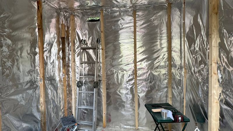 Foil insulation lining the walls and ceiling of a sauna shell with battens fixed
