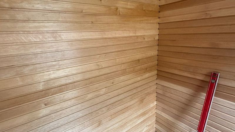 Fresh cedar panelling meeting at a corner with a spirit level leaning against it