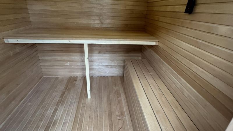 Sauna interior with warm indirect LED strips along the ceiling and two bench levels
