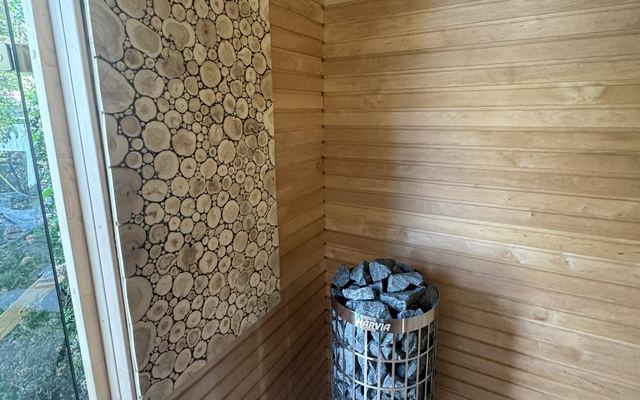Cylindrical stone sauna heater beside a log-end feature panel, ready for commissioning