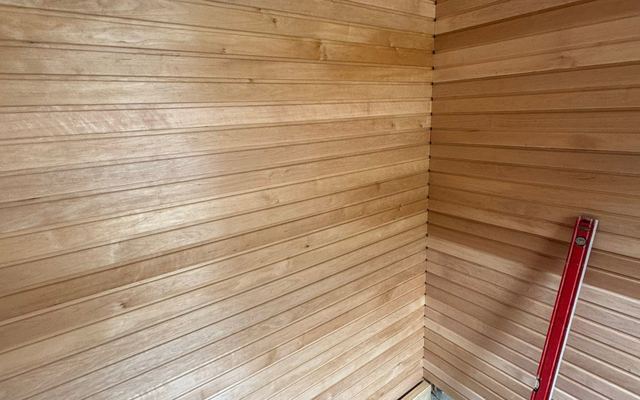Fresh cedar tongue-and-groove panelling being checked true with a spirit level